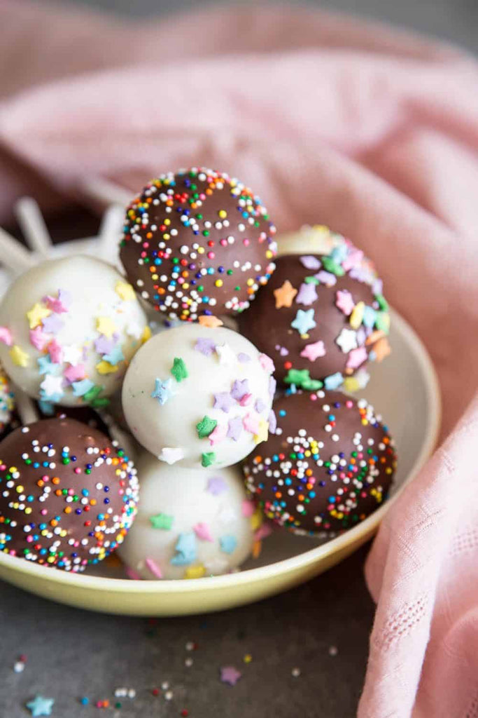 Cake Pops are the cutest desserts for any celebratory occasions! These pretty cake pops are made with vanilla cake mixed with cream cheese frosting, covered with melted chocolate and festive sprinkles.